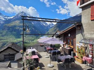 a patio with tables and chairs with mountains in the background at Osteria Anzonico in Anzonico