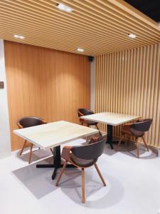 two tables and chairs in a room with wooden walls at BEAVER HOTEL and RESIDENCES in Cebu City