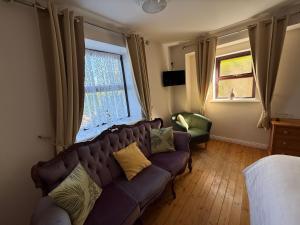 a living room with a couch and two windows at Kerry Ocean Lodge Room only in Glenbeigh