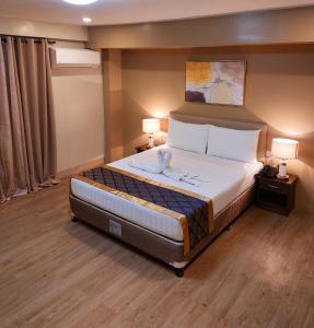 a bedroom with a large bed with two lamps at BEAVER HOTEL and RESIDENCES in Cebu City