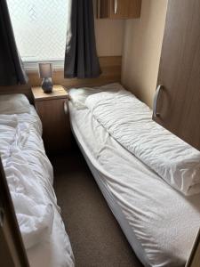 two unmade beds in a room with a window at Bobby's Bolthole in Heysham