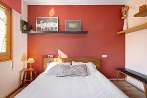 a bedroom with a red wall with a bed at Casa Abril in L'Ampolla