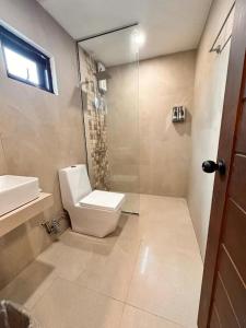 a bathroom with a toilet and a glass shower at KJSGrandeInn in Manolo Fortich +19 photos