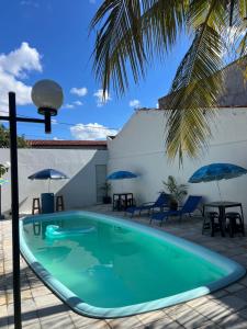 a pool with chairs and umbrellas next to a building at É de casa unidade 01- JUAZEIRO DO NORTE in Juazeiro do Norte