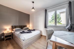 a bedroom with a bed and a table and a window at Appartement Cosy Parc Thermal in Thonon-les-Bains