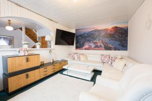 a living room with white furniture and a painting on the wall at Drevenička U Ježka in Ždiar