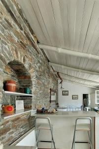 a kitchen with a stone wall and a counter with stools at Stone Kypri Apartment Andros in Kipri