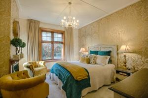 a bedroom with a bed and a chair and a chandelier at The Terrace - Luxury Villa in the heart of Oamaru in Oamaru