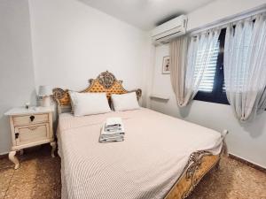 a bedroom with a bed and a window with curtains at On the Beach Oliva in Oliva