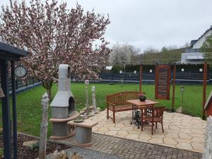 a patio with a bench and a table and a tree at Achims Hüttl in Bad Berka