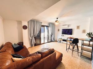 a living room with a brown couch and a desk at On the Beach Oliva in Oliva