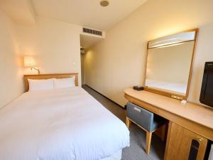 a hotel room with a bed and a desk with a mirror at THE DAY HOTEL ShinYokohama in Yokohama