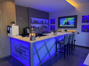 a bar in a room with purple lighting and stools at Confidence Hotel Viadana in Viadana
