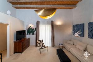 a living room with a couch and a television at Casa Philomena - Fascino storico in centro in Noto