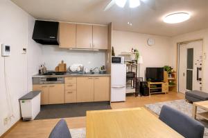 a kitchen and living room with a refrigerator and a table at Yoshimi Stay Kawaguchi in Kawaguchi