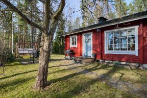 a red house with a tree in the yard at Holiday Cabin Kukkula - AC, fireplace & wood-fired sauna in Porvoo