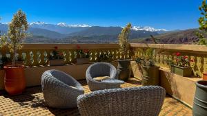 a balcony with wicker chairs and potted plants and mountains at Bihi Lodge in Tahannout