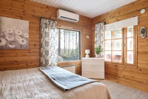 a bedroom with wooden walls and a bed and a window at Holiday Cabin Kukkula - AC, fireplace & wood-fired sauna in Porvoo