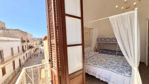 a bedroom with a canopy bed and a balcony at Al centro con panorama Favignana Isole Egadi in Favignana