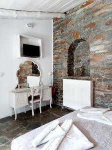 a bedroom with a brick wall with a bed and a desk at Stone Kypri Apartment Andros in Kipri