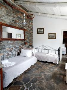 a bedroom with two beds and a stone wall at Stone Kypri Apartment Andros in Kipri