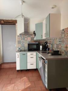a kitchen with blue cabinets and a tile floor at Gîte Rabanier in Saint-Ciers-dʼAbzac +6 photos