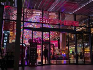 a man standing in front of a building with a neon sign at Baan Rak BTS phromphong Emsphere in Bangkok