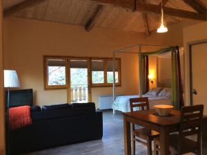 sala de estar con sofá, mesa y cama en Els Apartaments del bosc, en Ribes de Freser