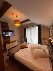 a bedroom with a large bed and a flat screen tv at Garden Apart in Predeal