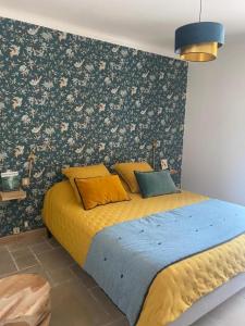 a bedroom with a bed with yellow sheets and floral wallpaper at Maison Terre de Lune in Mondragon