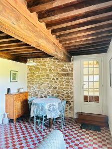 a table and chairs in a room with a stone wall at La maisonnette du Morvan in Cussy-en-Morvan