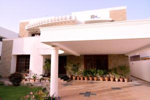 a white building with potted plants in a courtyard at Elevé Stays - Boutique Family Suites in Karachi