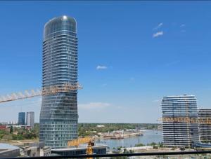 a tall glass building with a bridge in the background at Belgrade Waterfront Wolf in Sajmište