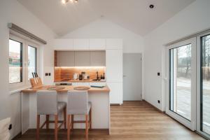 a kitchen with white cabinets and a counter with chairs at Domeček U Potoka in České Budějovice