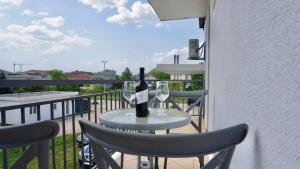 a table with a bottle of wine and two glasses on a balcony at Apartments St Jakov in Međugorje