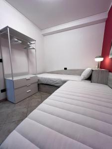 a white bedroom with two beds and a dresser at Appartamento 37 Varazze in Varazze