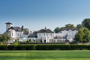 a row of white houses with a green lawn at Tullyglass House Hotel in Ballymena