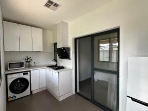 a small kitchen with white cabinets and a washer and dryer at June Stay in Perth