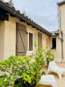 a house with a wooden door and a white chair at Hotel L'Escale in Aigues-Mortes