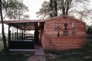 a small wooden shed with a porch and trees at De Wilg Beerse, tiny house with meadow view, animals in Beerse