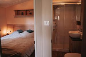 a bedroom with a bed and a bathroom with a sink at De Wilg Beerse, tiny house with meadow view, animals in Beerse