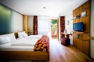 a bedroom with a bed and a television and a room at Holzschuhs Schwarzwaldhotel und Restaurant in Baiersbronn