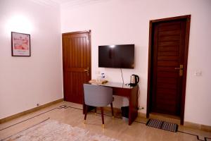 a room with a desk and a television on a wall at Elevé Stays - Boutique Family Suites in Karachi