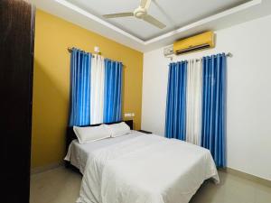 a bedroom with a large bed with blue curtains at two bedroom anandha vibes in Guruvāyūr