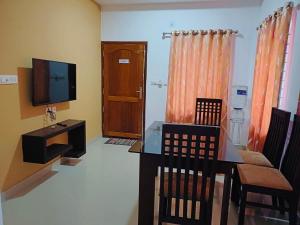 a living room with a dining table and a television at two bedroom anandha vibes in Guruvāyūr