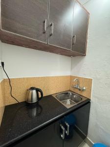 a kitchen counter with a sink and a tea kettle at two bedroom anandha vibes in Guruvāyūr