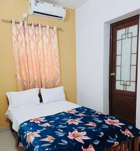 a bedroom with a bed with a blue and pink blanket at two bedroom anandha vibes in Guruvāyūr