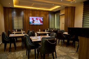 a dining room with tables and chairs and a flat screen tv at Motion Hotel and Suites, Uyo in Uyo
