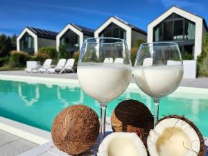 two glasses of white wine next to a swimming pool at NOVA ULINIA Sea - dom nad morzem, podgrzewany basen, sauna, balia z jacuzzi,Starlink in Ulinia
