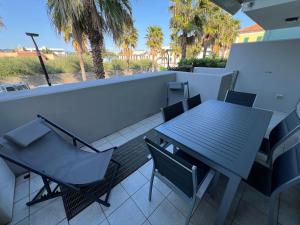 a table and chairs on a balcony with palm trees at Palm Grove House con terrazzo e box privato in Loano